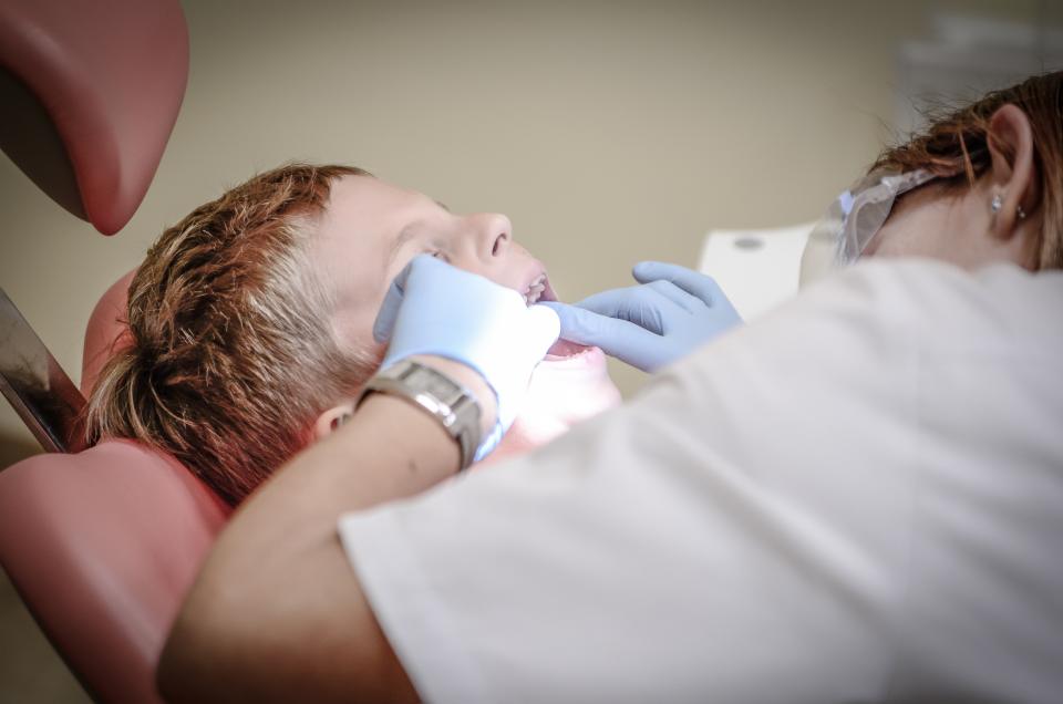 A dentist examining a young patient in a bright, modern orthodontic practice