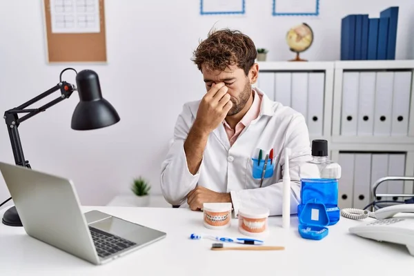 Tired dentist at his clinic desk, rubbing his eyes after another month of marketing spend without results